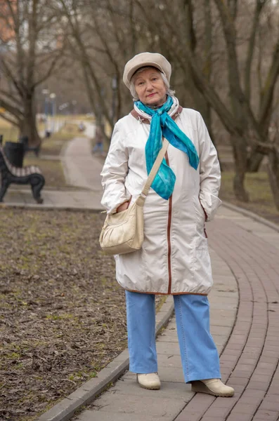 早春的时候 一位衣着华丽的老妇人在公园的小巷里散步 — 图库照片