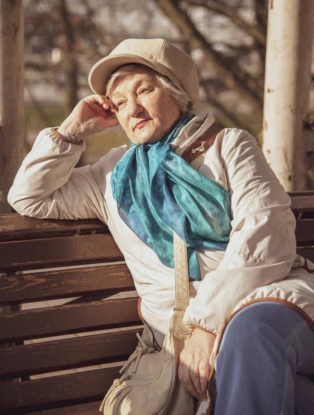 早春的时候 一位优雅的白发苍苍的老妇人坐在公园的长椅上 — 图库照片