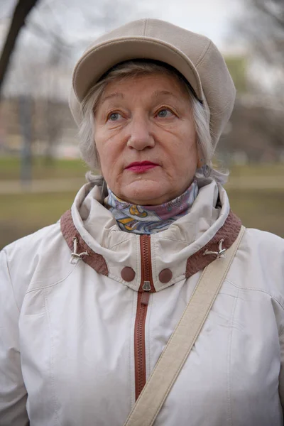 在自然的背景下 一个头戴浅色贝雷帽的老年白发女人的巨大的垂直画像 — 图库照片