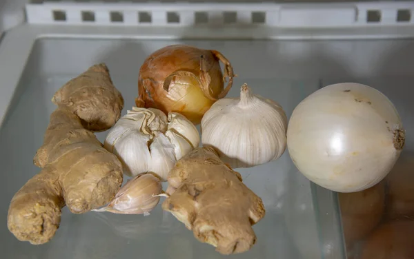Onion, garlic and ginger on the shelf in the refrigerator. Alternative medicine, nutritional supplements. Useful products for the prevention of diseases.