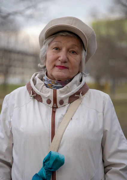 在公园散步时 一个穿着时髦贝雷帽的优雅老妇人的垂直肖像 — 图库照片