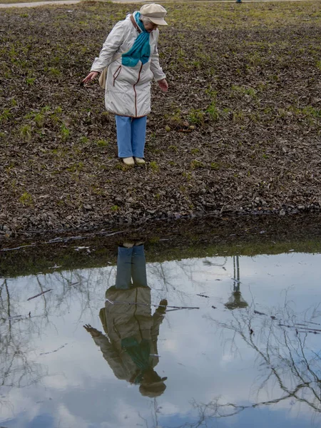 Une femme âgée en promenade dans le parc au bord de l'étang . — Photo