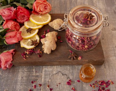 Zencefil, bal ve tahtanın üzerinde bir kavanoz kurutulmuş gül yaprağı. 