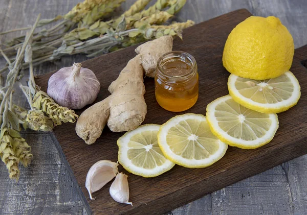 Gingembre, citron, ail et thé de Mursal de montagne sur une planche de bois rugueuse . — Photo