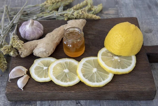 Gingembre, citron, ail et thé de Mursal de montagne sur une planche de bois rugueuse . — Photo