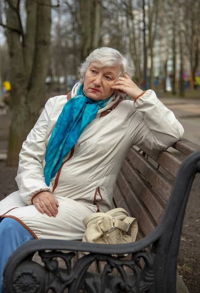 一位优雅的白发老妇人坐在公园的长椅上. — 图库照片