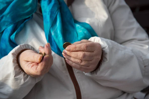 Die faltigen Hände einer alten Frau, die durch kleine Münzen sortiert. — Stockfoto