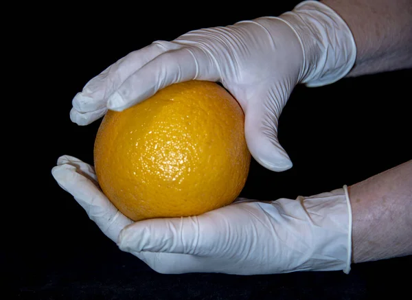 Hands Elderly Woman White Rubber Gloves Hold Large Bright Orange — Stock Photo, Image
