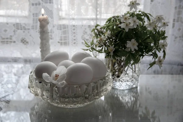精美的复活节依然以白色的色调生活着 玻璃瓶中的春天花朵 白色背景中的水晶花瓶中的白蛋 — 图库照片