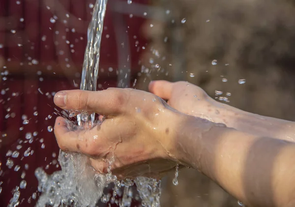 Mannelijke handen onder een stroom van water . — Stockfoto