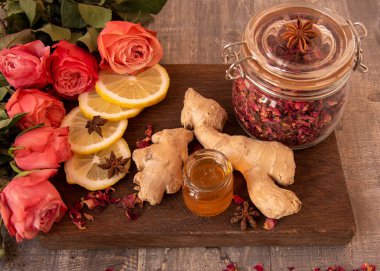 Güzel bir buket gül, bir kavanoz kuru gül yaprakları, bal ve aromatik baharatlar ahşap bir arka planda.. 