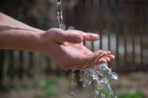 Mannelijke handen onder een stroom van water . — Stockfoto