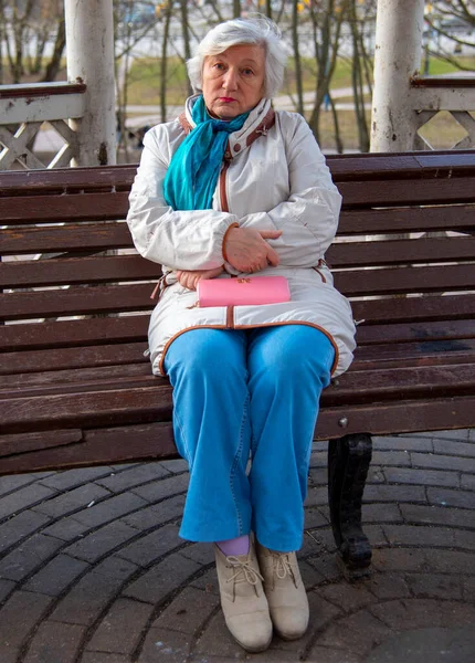 一位老妇人正坐在长椅上 . — 图库照片