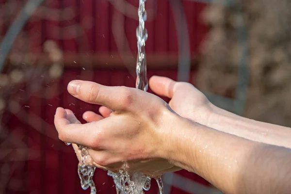 Mannelijke handen onder een stroom van water . — Stockfoto