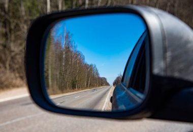 Arabanın dikiz aynasında yolun yansıması var. Seyahat, gezmek.