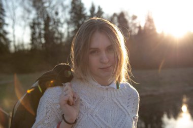 Güneşin arka planında, doğanın arka planında açık renk saçlı güzel bir kız. Yatay portre.