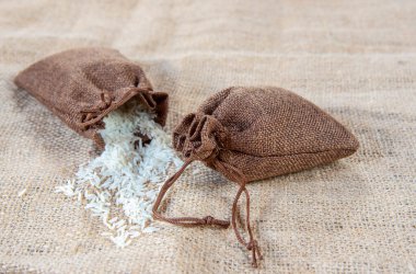 Mısır gevreğiyle doldurulmuş iki çuval bez. Bir tanesi çarşaf bezine pirinç döküyor. Sağlıklı yiyecekler, doğal çevre dostu malzemeler..