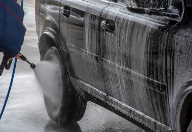 Bir adam oto yıkamada araba yıkıyor.. 