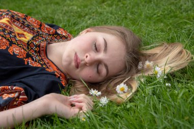 Etnik kıyafetli bir kız açık bir alanda uyuyor. .