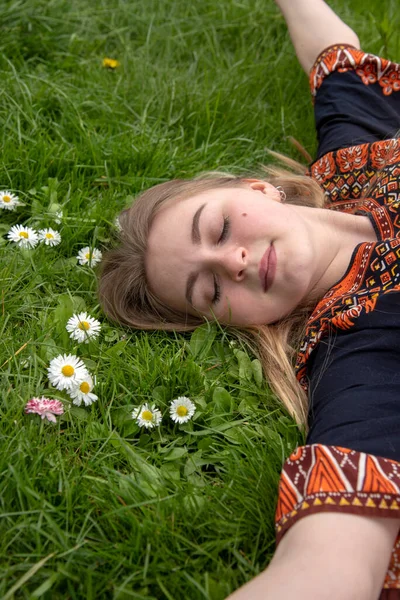 Een meisje in een etnische jurk slaapt op een open plek. . — Stockfoto