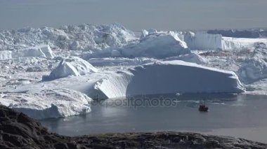 Ilulissat Grönland köy alanında batan güneşin ışınları tarafından aydınlatılmış büyük bir buzul boyunca yelken
