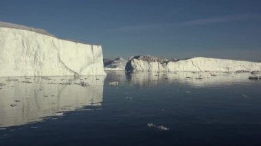 Ilulissat Grönland köy alanında batan güneşin ışınları tarafından aydınlatılmış büyük bir buzul boyunca yelken
