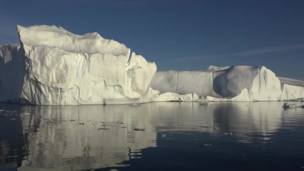 イルリサットのグリーンランド村の領域に夕日の光に照らされた巨大な氷河に沿ってセーリング — ストック動画