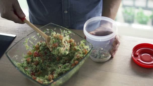 Hombre poner ensalada en caja de plástico en la cocina de cámara lenta — Vídeo de stock