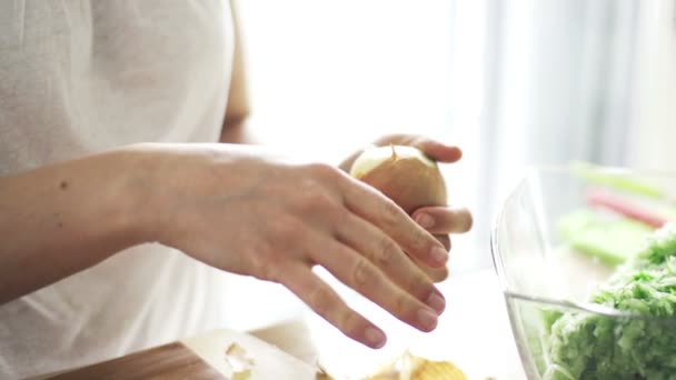 Mujer manos pelando cebolla en la cocina — Vídeo de stock