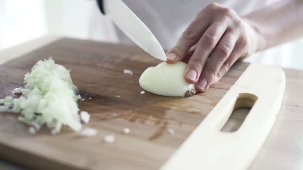 Frau schneidet Zwiebel in Zeitlupe auf Schneidebrett in der Küche — Stockvideo