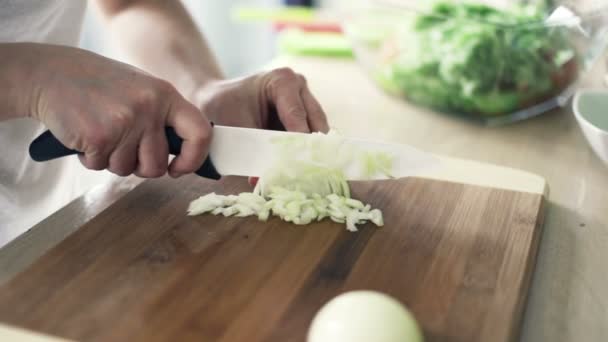 Mujer rebanando cebolla en la tabla de cortar en la cocina a cámara lenta — Vídeo de stock