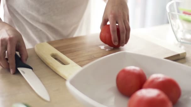 Frau schneidet Tomate in Zeitlupe auf Schneidebrett in der Küche — Stockvideo