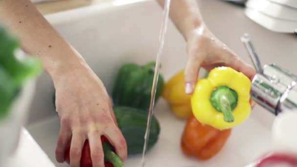 Γυναίκα πλύσιμο πιπέρι κάτω από το νερό της βρύσης αργή κίνηση — Αρχείο Βίντεο