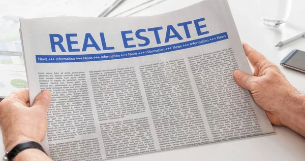 Homem lendo jornal com a manchete Real Estate — Fotografia de Stock