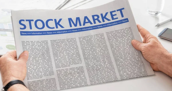 Hombre leyendo el periódico con el titular de la Bolsa —  Fotos de Stock