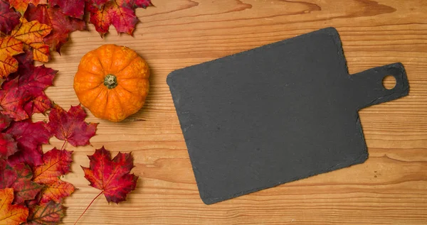 Autumn foliage with a pumpkin and an empty blackboard — Stock Photo, Image