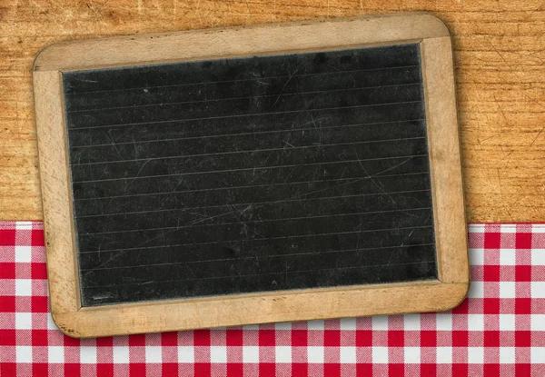 Blackboard on wooden background with a red checkered tablecloth — Stock Photo, Image