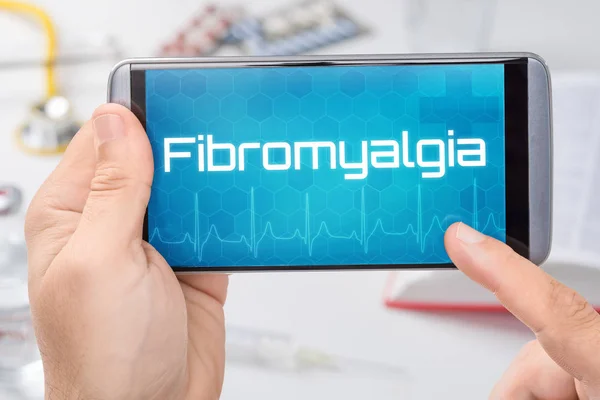 Smartphone con el texto Fibromialgia en la pantalla — Foto de Stock