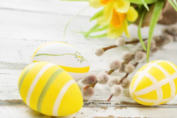 Yellow easter eggs on a rustic background with daffodils — Stock Photo, Image