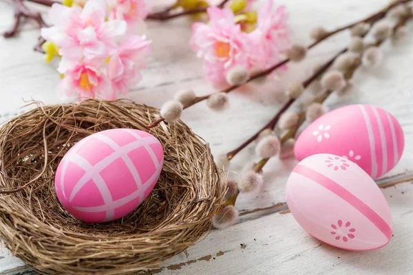 Un nido de Pascua con huevos rosados de Pascua sobre un fondo de madera —  Fotos de Stock