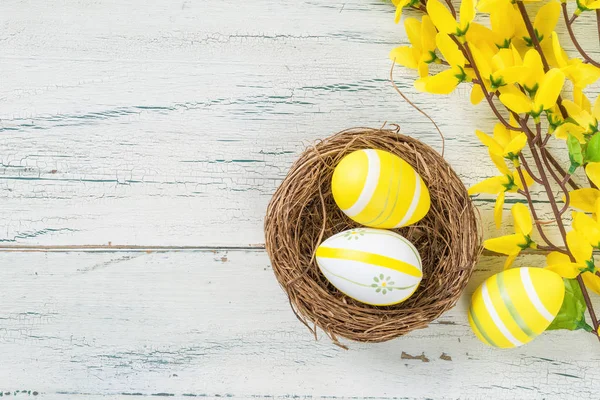 Un nid de Pâques avec des œufs de Pâques jaunes sur un fond en bois — Photo