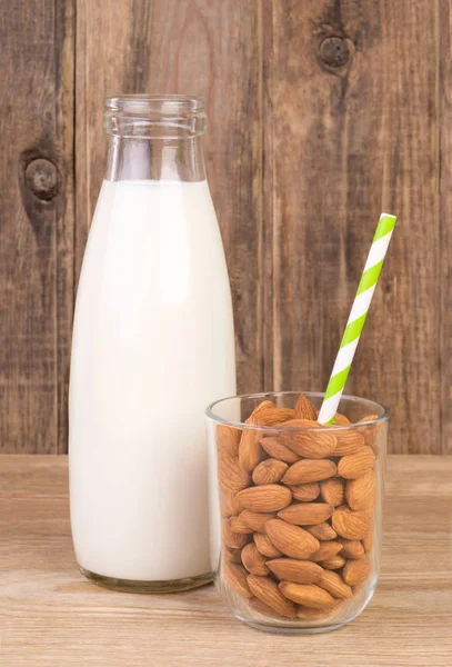 Mandlové mléko v láhvi a mandle ve sklenici — Stock fotografie
