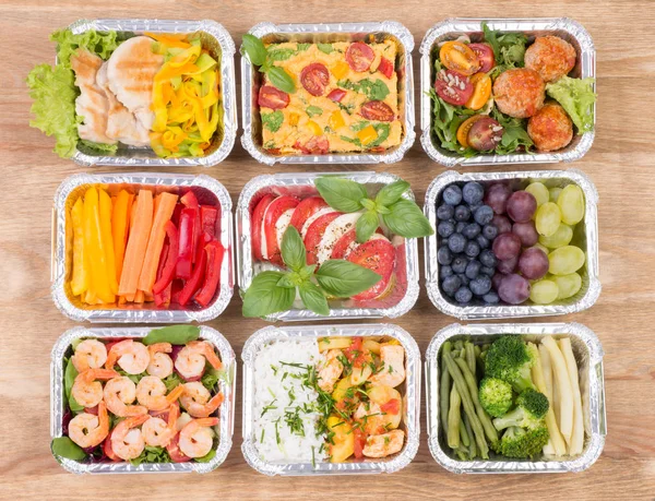 Healthy meals and salads in boxes on wooden table, top view