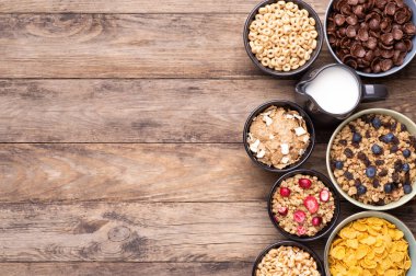 Kahvaltılık gevrekler kaselerde bir sürahi süt kırsal ahşap masa üzerinde, fotokopi alanı ile üst manzara