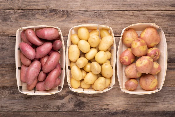 不同类型的土豆放在木制乡村桌子上的箱子里 — 图库照片