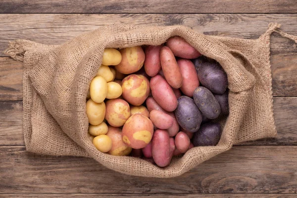 Diferentes Tipos Batatas Saco Mesa Rústica Madeira — Fotografia de Stock