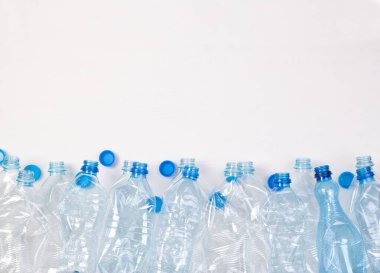 Beyaz arka planda fotokopi alanı olan bir sürü plastik şişe.