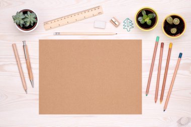 Üzerinde ahşap kalem, kalem ve fotokopi alanı olan kahverengi kağıt gibi çevre dostu ofis malzemeleri olan bir masa.