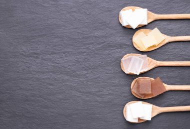 Tahta kaşıklarda beş çeşit gliserin sabun bazlı siyah taş zemin üzerinde fotokopi alanı