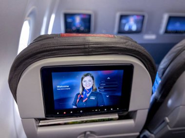 Saint Louis, MONov 18, 2020; personal video devices on back of seat head rests on American Airlines plane display a safety message from crew members before take off of Boeing 737.